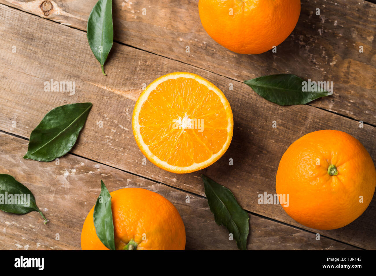 Fresh oranges and leaves on wooden board background Stock Photo