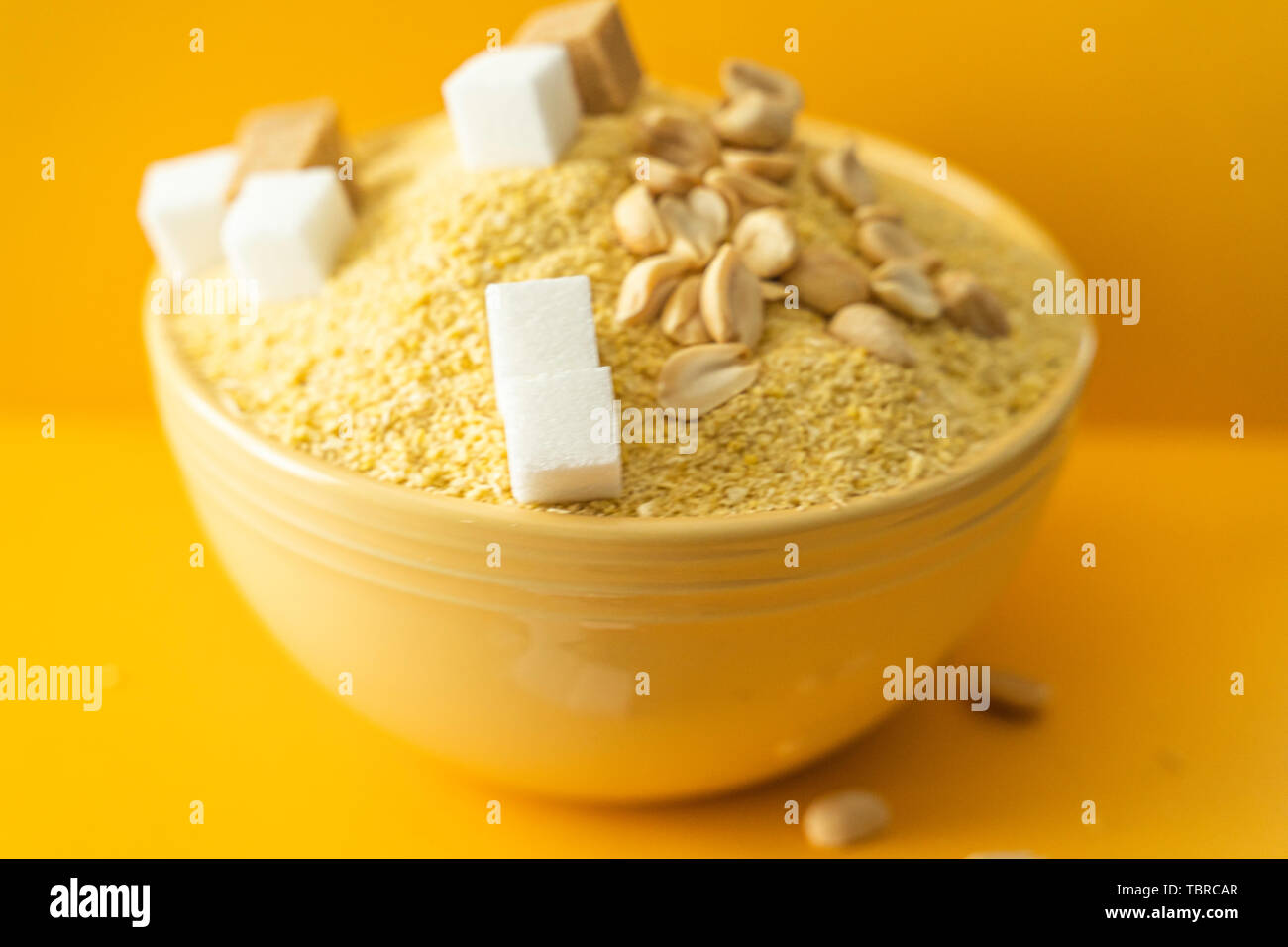 Bowl of Nigerian Yellow Garri in Yellow bowl with Peanuts and Sugar