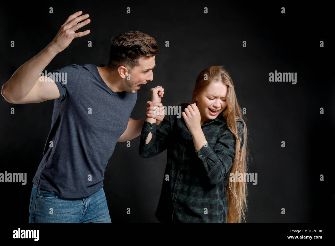 Young quarrelling couple on dark background Stock Photo