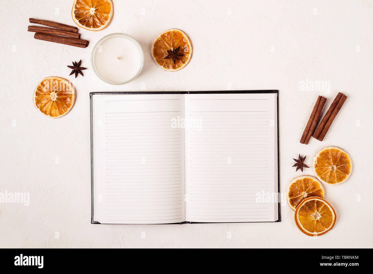 Notepad candle and autumn spices on white table. Stock Photo