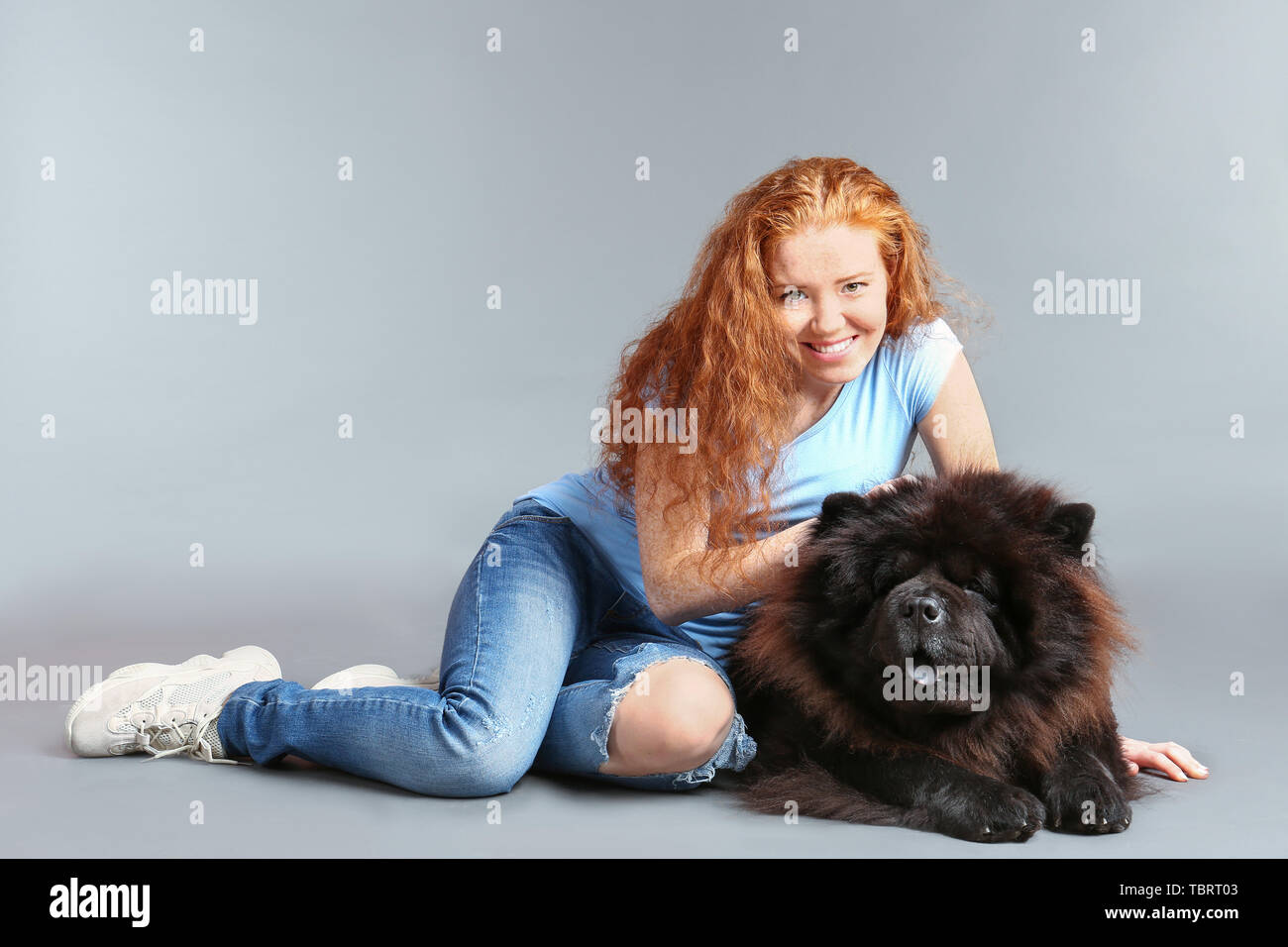 Young woman with cute Chow-Chow dog on grey background Stock Photo
