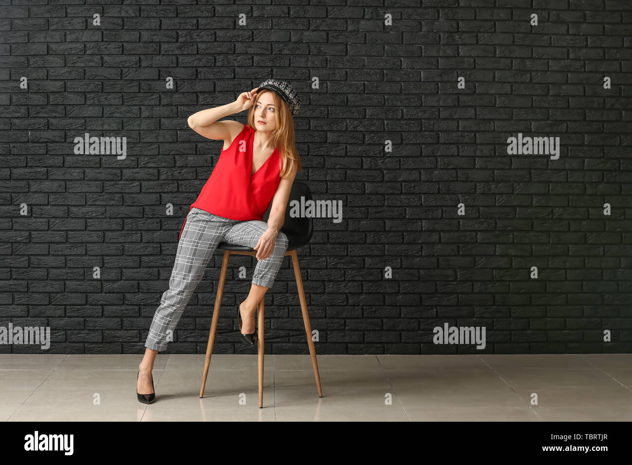 Portrait of mature woman sitting on chair against dark wall Stock Photo ...