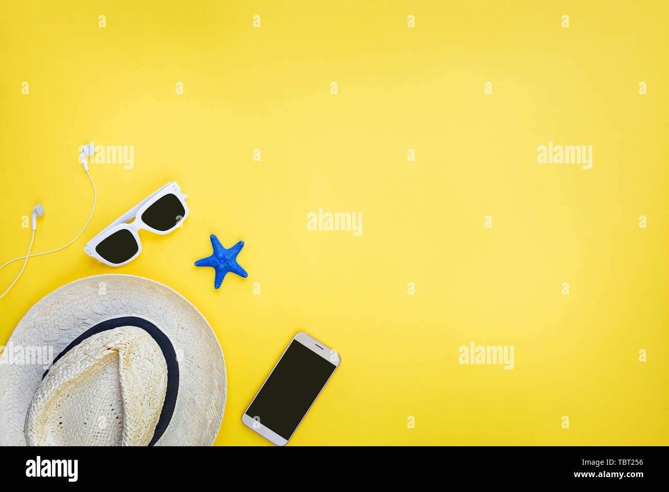 Summer vacation background - straw hat, sunglasses and smart phone over yellow background= Stock Photo