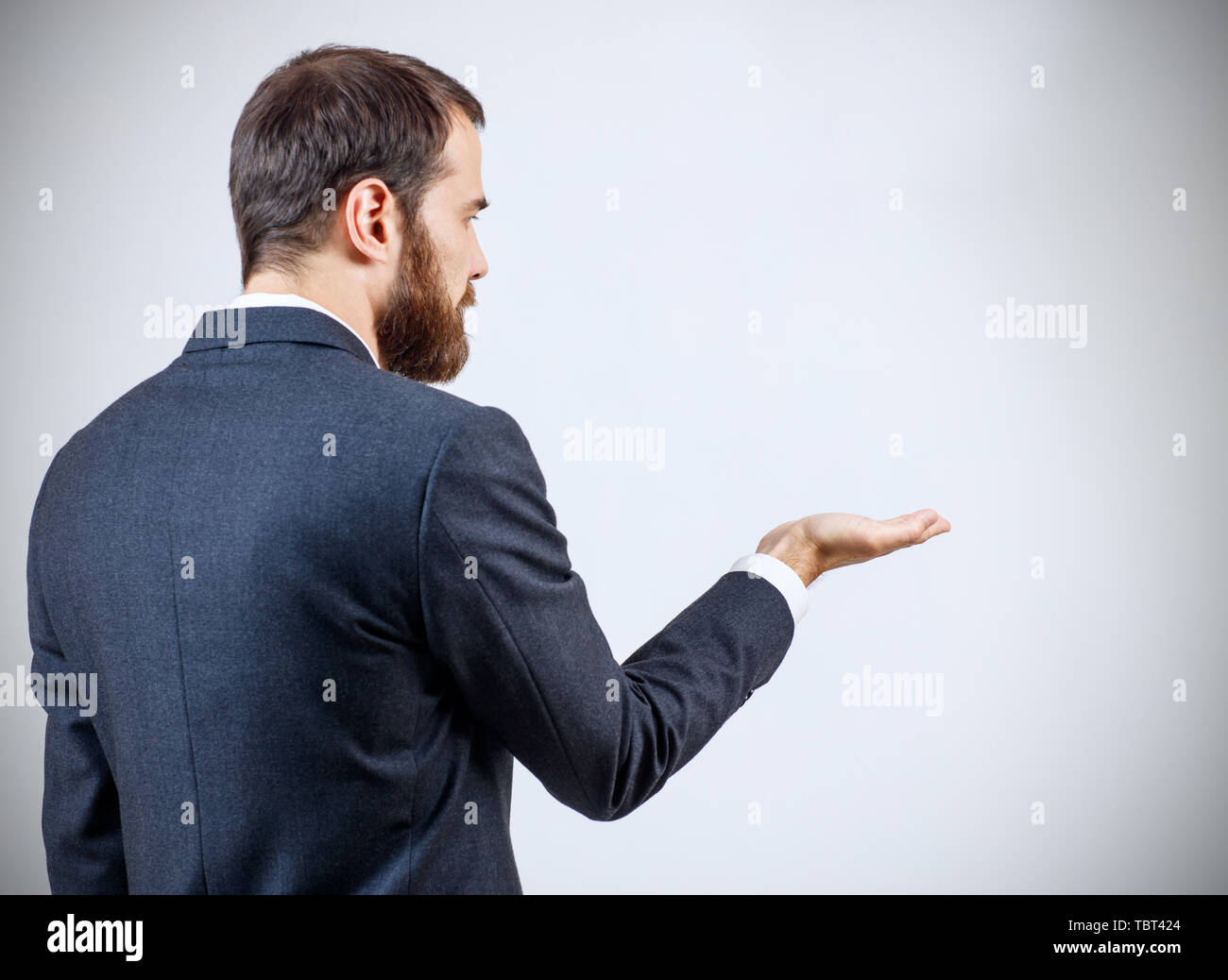 Businessman in suit standing and shows outstretched hand with open palm. Stock Photo