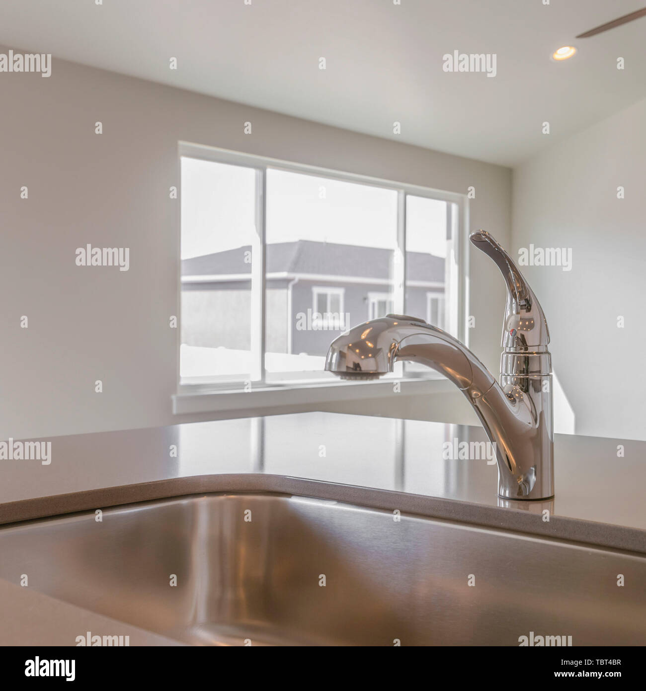 Square Shiny kitchen counter top with sink and faucet inside a new home