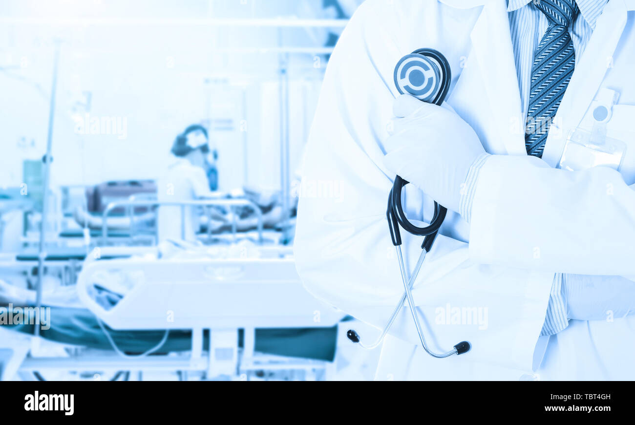 Asian doctor holding stethoscope on blurred nurse nursing patient in hospital room use us hospital background Stock Photo