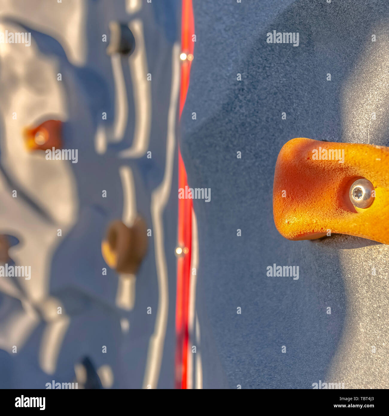 Square Bright orange foothold or handhold of a climbing wall at a playground Stock Photo