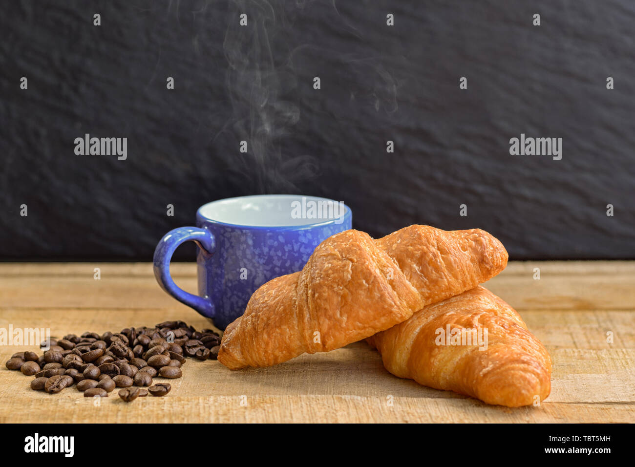 croissant and cup of coffee on wooden table Stock Photo