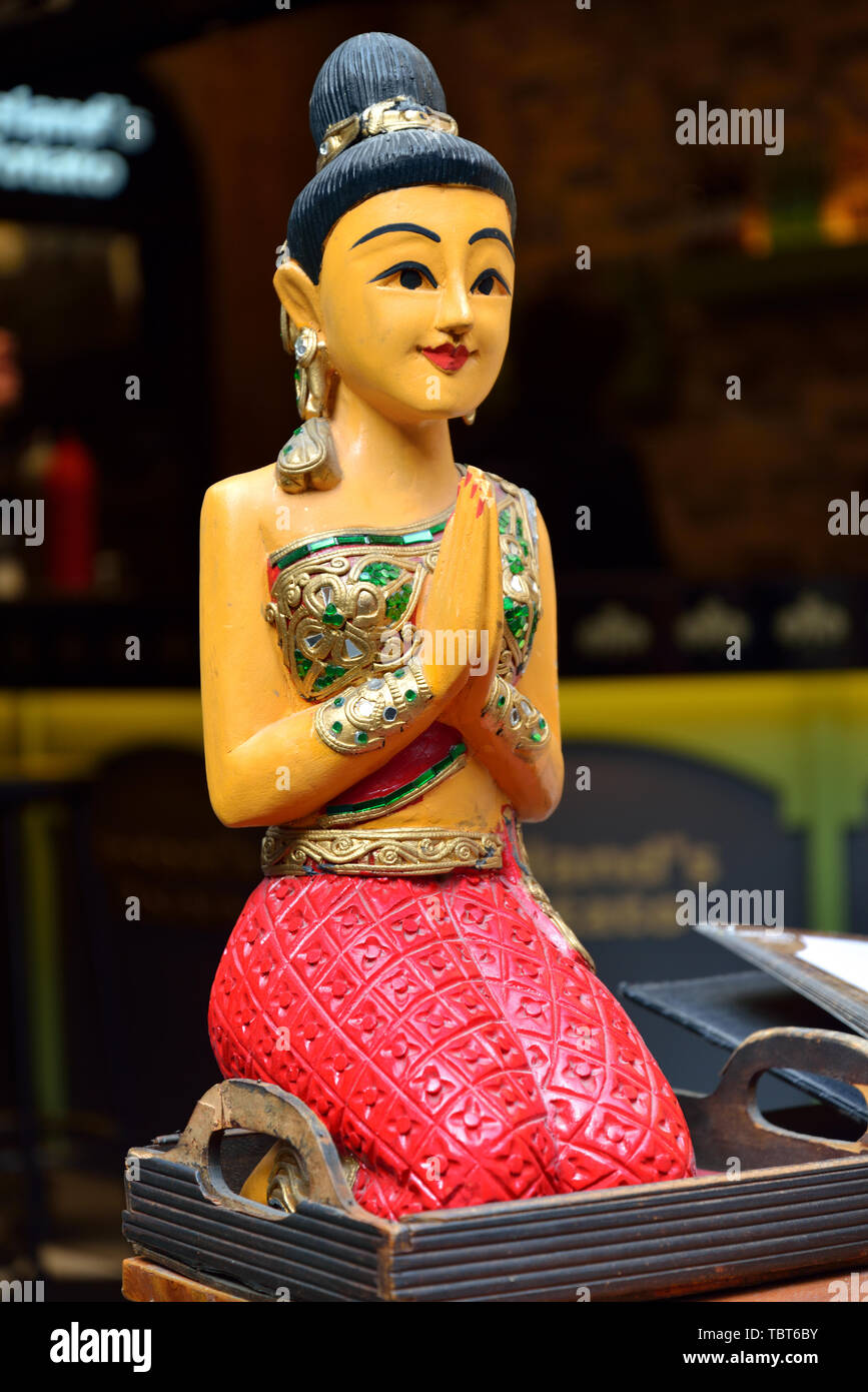 Statue of women kneeling in front of Thai restaurant Stock Photo