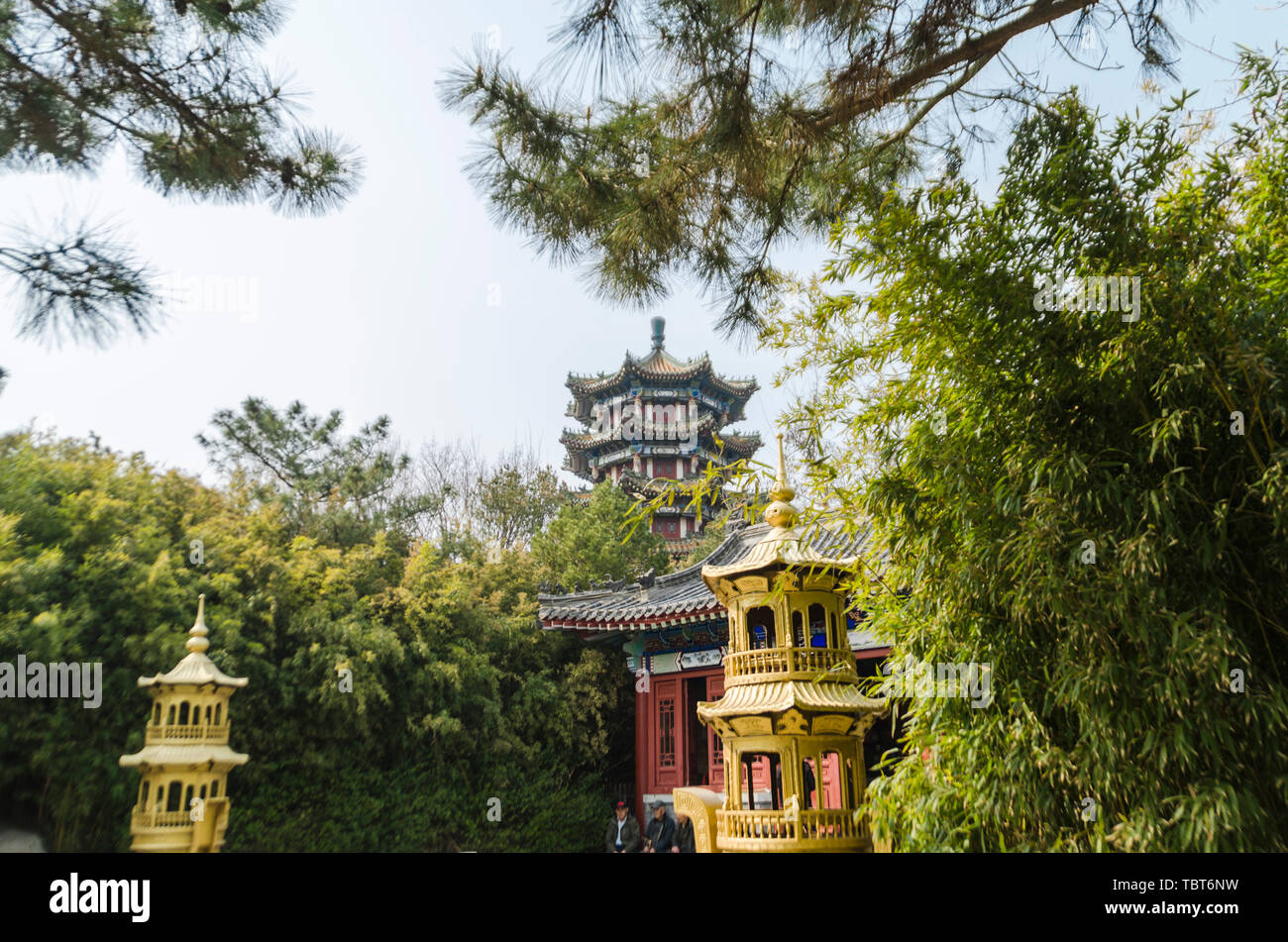 The golden gourd-topped incense stove in front of the Taoist door of Li Cun Park in Qingdao echoes the temple pagoda in the distance. Stock Photo