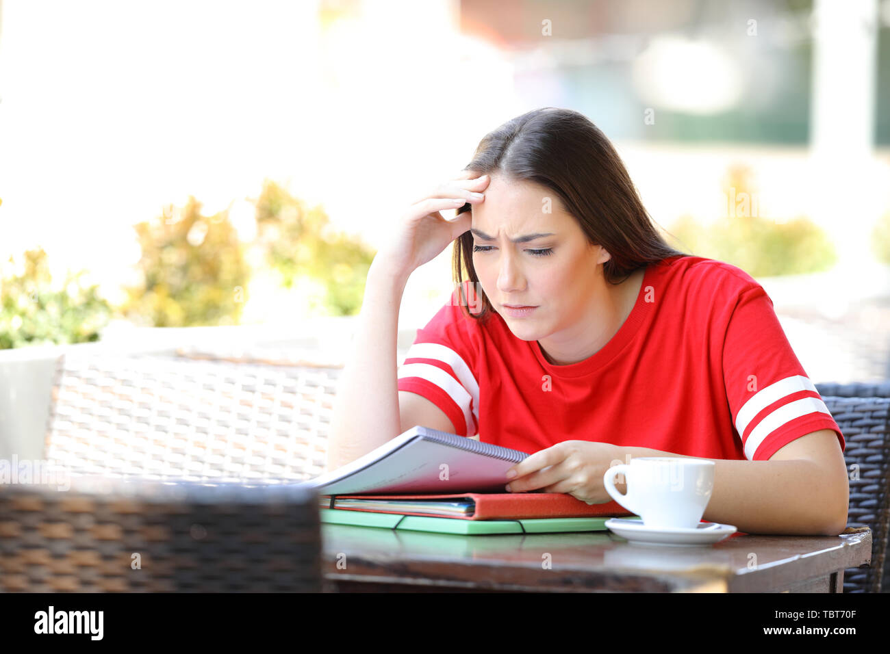 Worried student trying to understand lesson reading notes sitting in a coffee shop terrace Stock Photo
