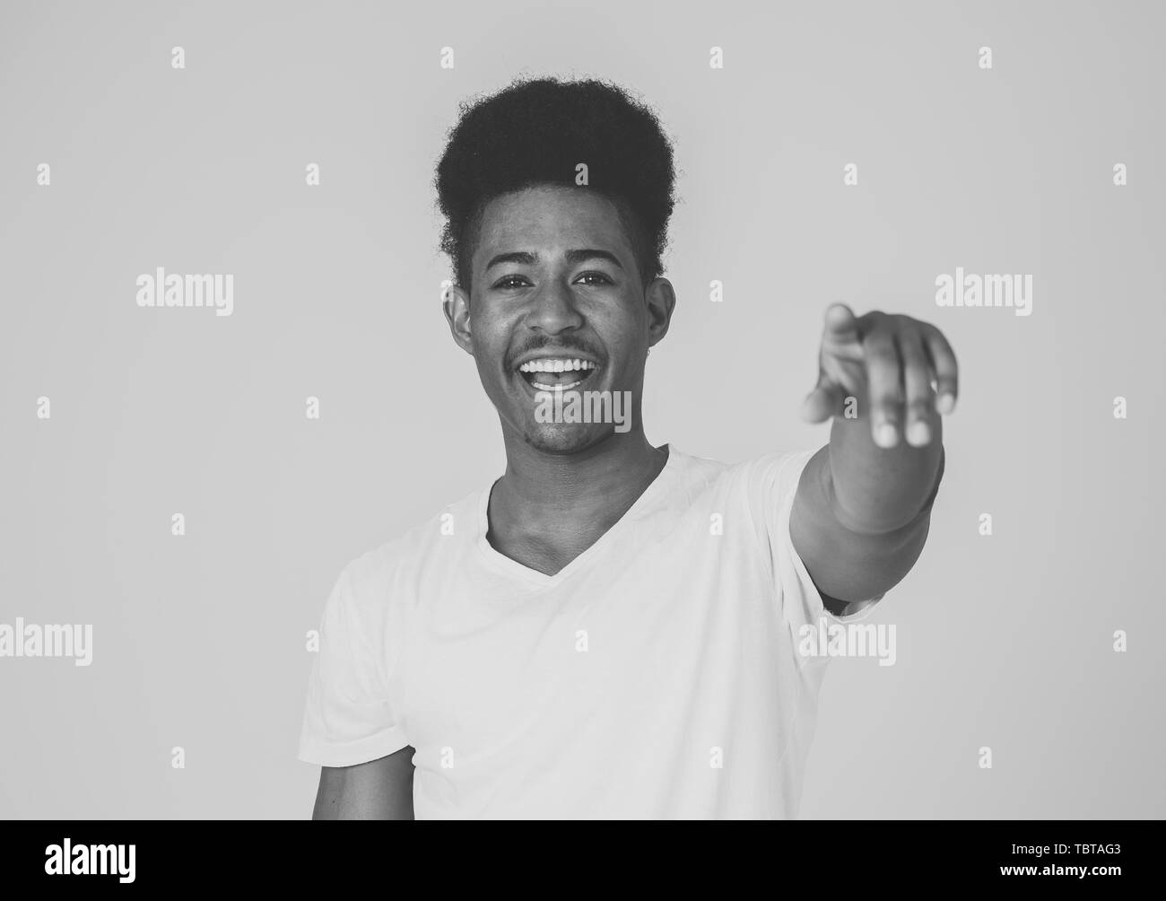 Portrait of handsome shocked african american man pointing out and laughing with surprised and happy face. Teenager laughing at something funny. Facia Stock Photo