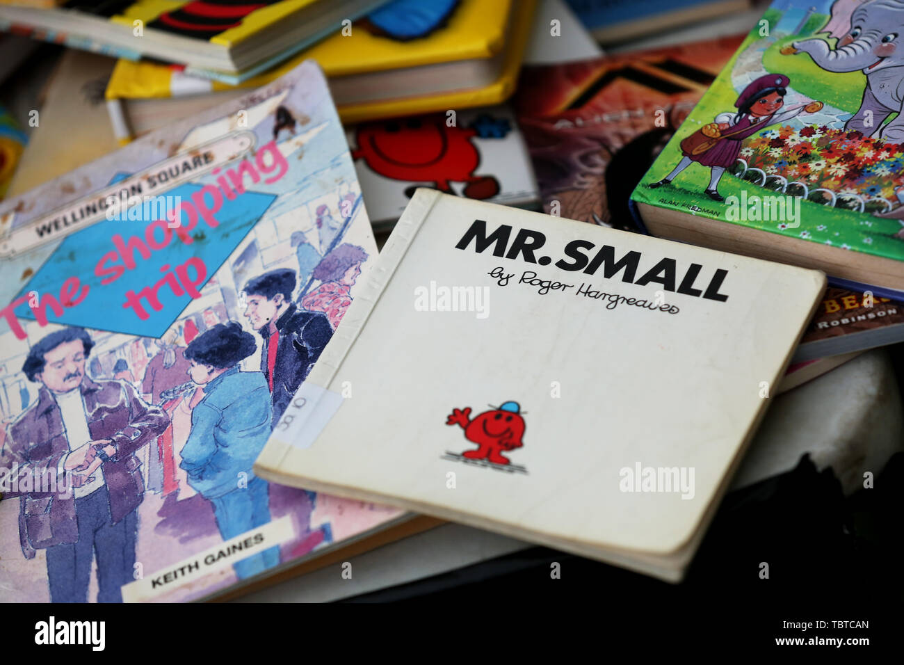 Pile of children's books for sale on a charity stall in Sussex, UK