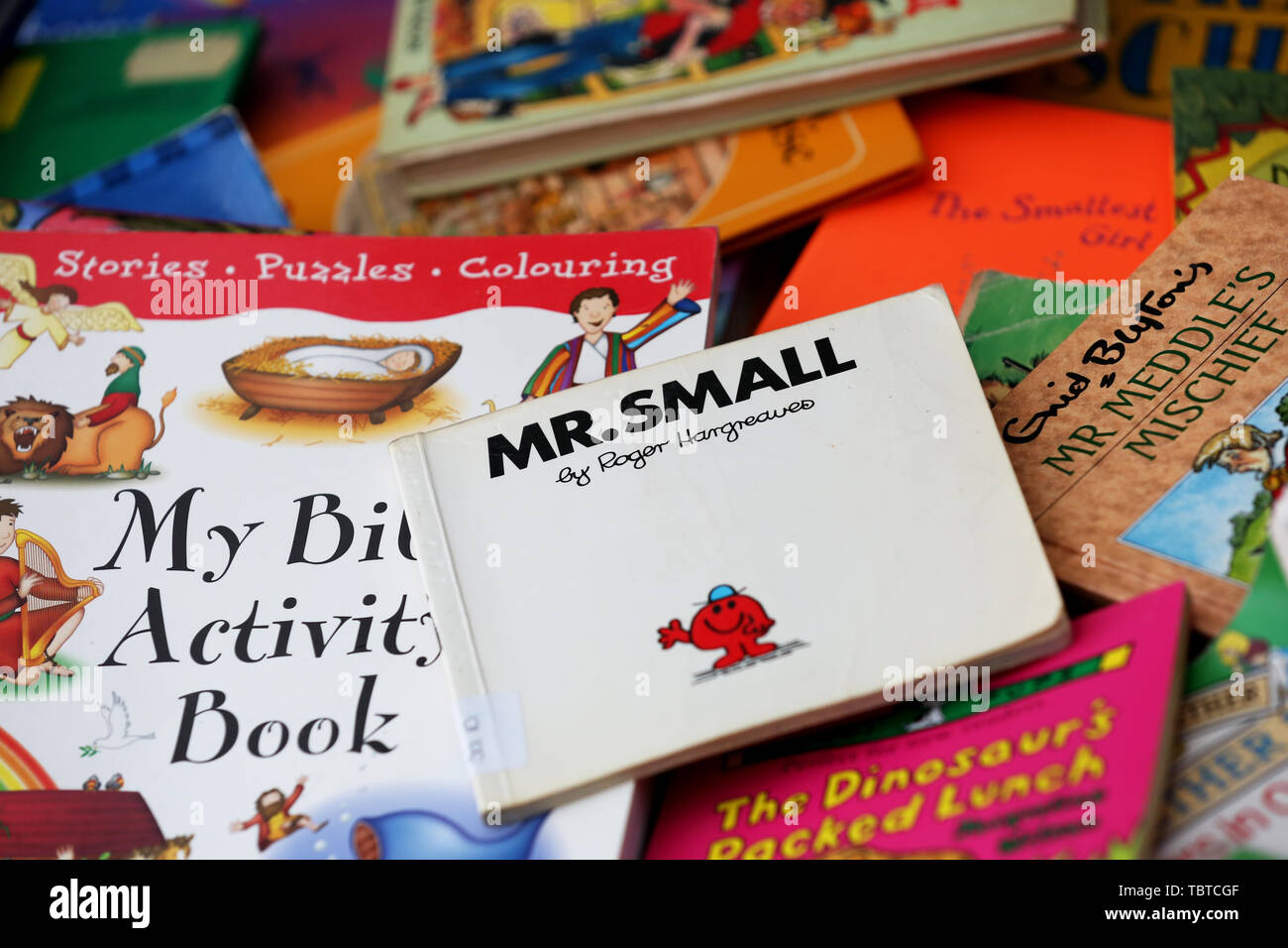 Pile of children's books for sale on a charity stall in Sussex, UK