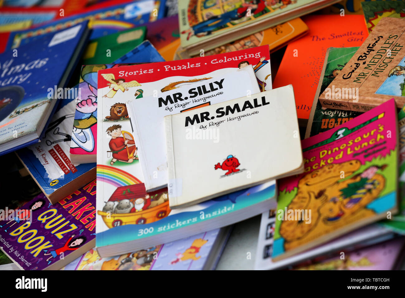 Pile of children's books for sale on a charity stall in Sussex, UK