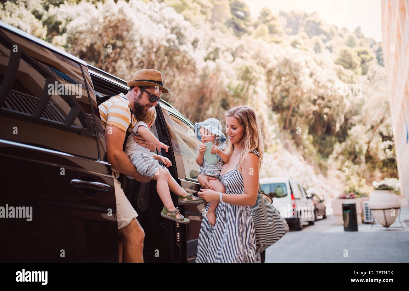 A young family with two toddler children getting out of taxi on summer holiday. Stock Photo
