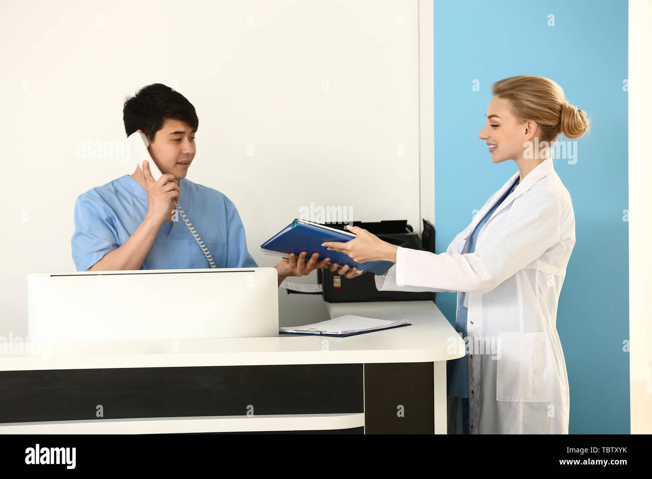 Female doctor giving documents to receptionist in clinic Stock Photo