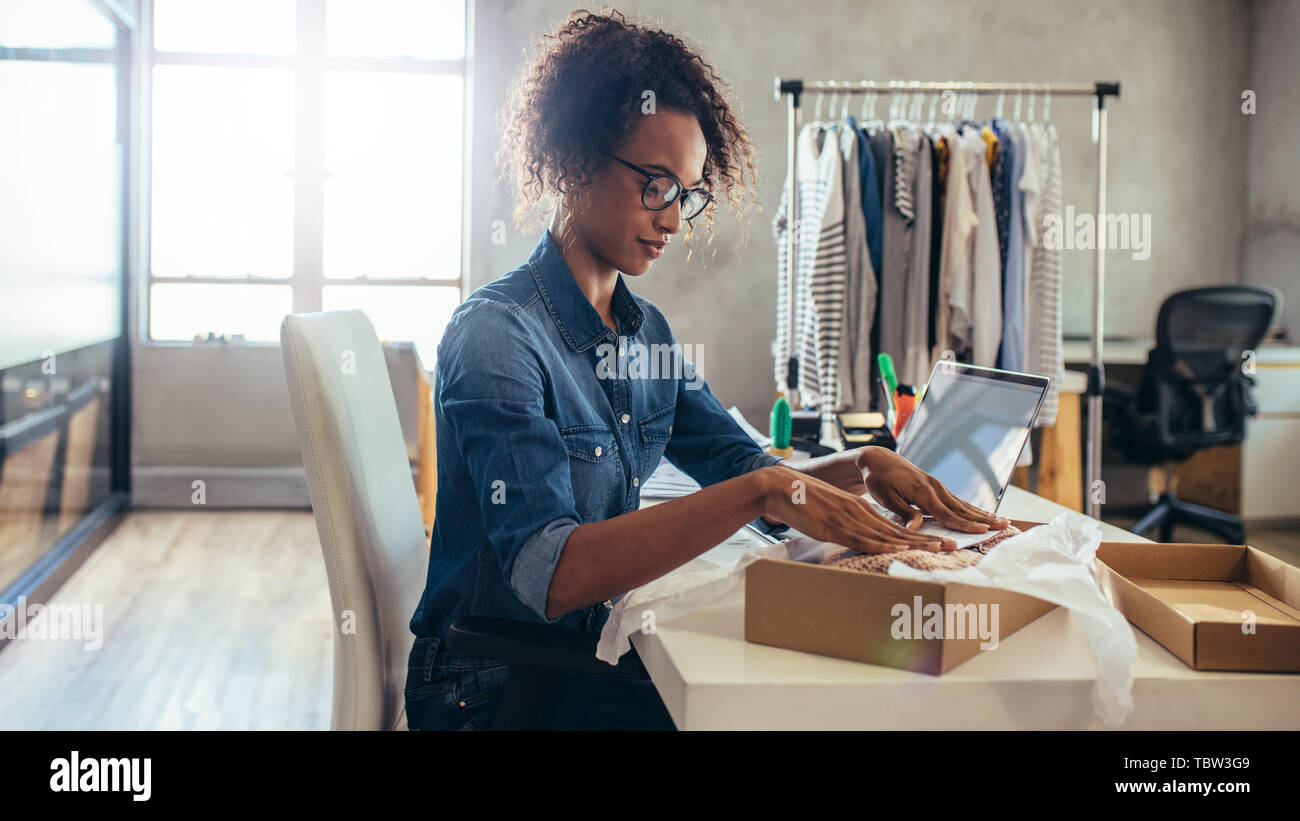 Woman online entrepreneur packing parcel box at office. Woman seller preparing product for delivery. Stock Photo