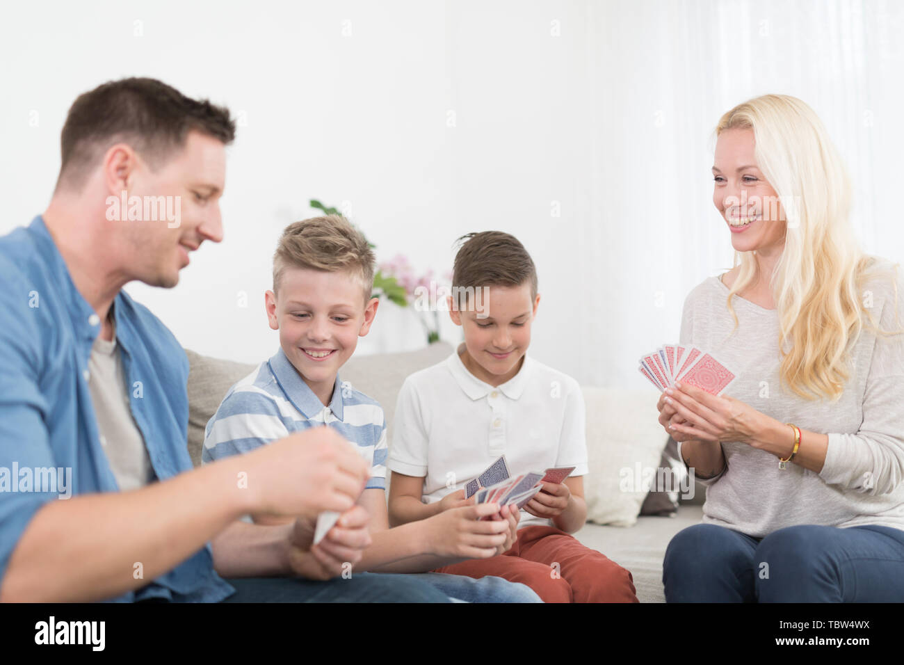 Happy young family playing card game at home. Stock Photo