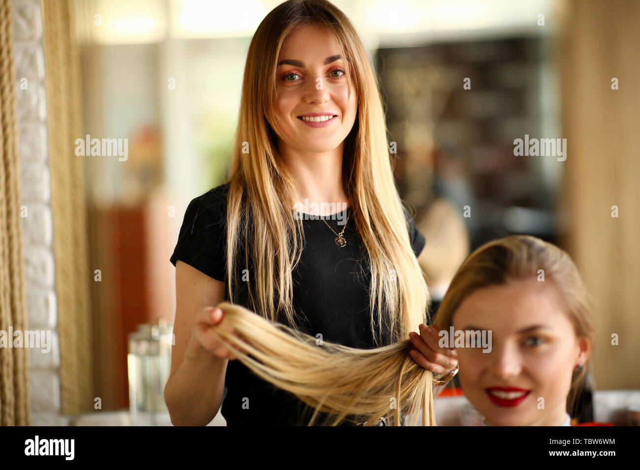 Young Hairdresser Holding Hair of Female Client. Smiling Hairstylist  Picking Haircut for Girl. Two Blonde Woman in Beauty Salon. Stylist  Beautician St Stock Photo - Alamy