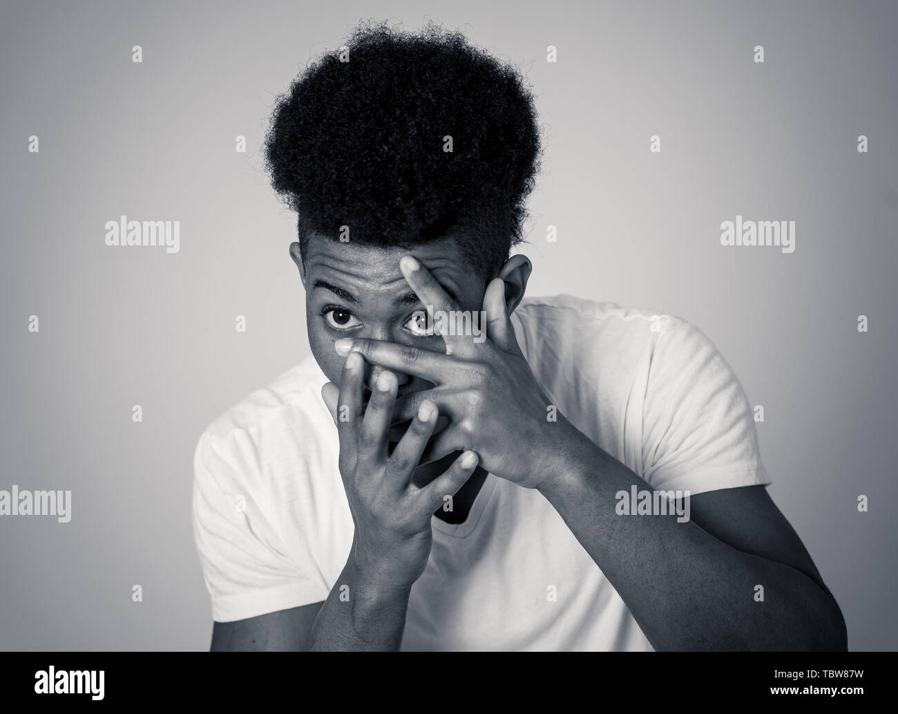 Portrait of young african american man feeling scared and shocked. Teenager disgusted at something that is happening covering his face. In horror and  Stock Photo
