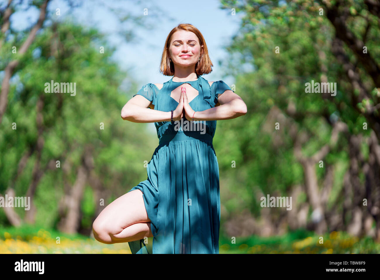 Portrait Of Woman In Long Green Dress Doing Yoga In Forest Stock
