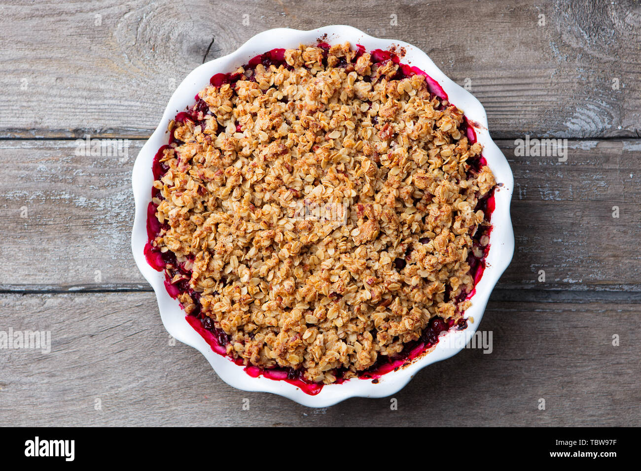 Berry crumble, crisp in baking dish. Wooden background. Top view. Stock Photo