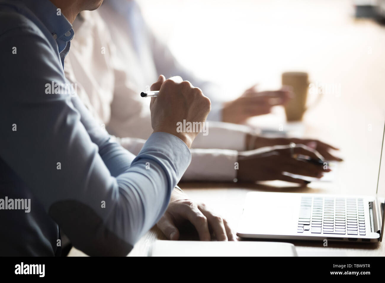Close up multiracial employees sitting in boardroom at meeting Stock Photo