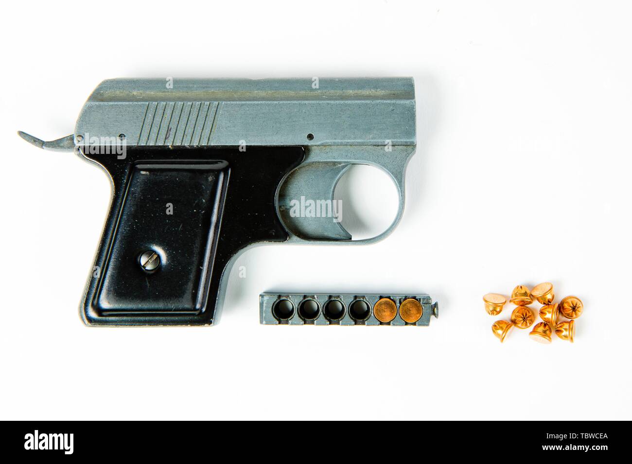 Old gray alloy starter pistol with black grip and small dummy ammunition an magazine Stock Photo