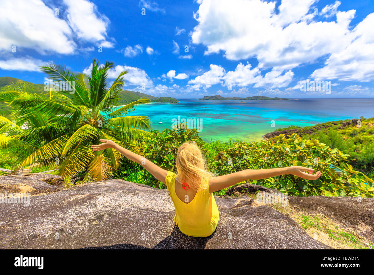 Top view panorama of Praslin, Seychelles. Carefree woman in yellow dress enjoying amazing views of Anse of Gouvernement overlooking Cote d'Or Bay with Stock Photo