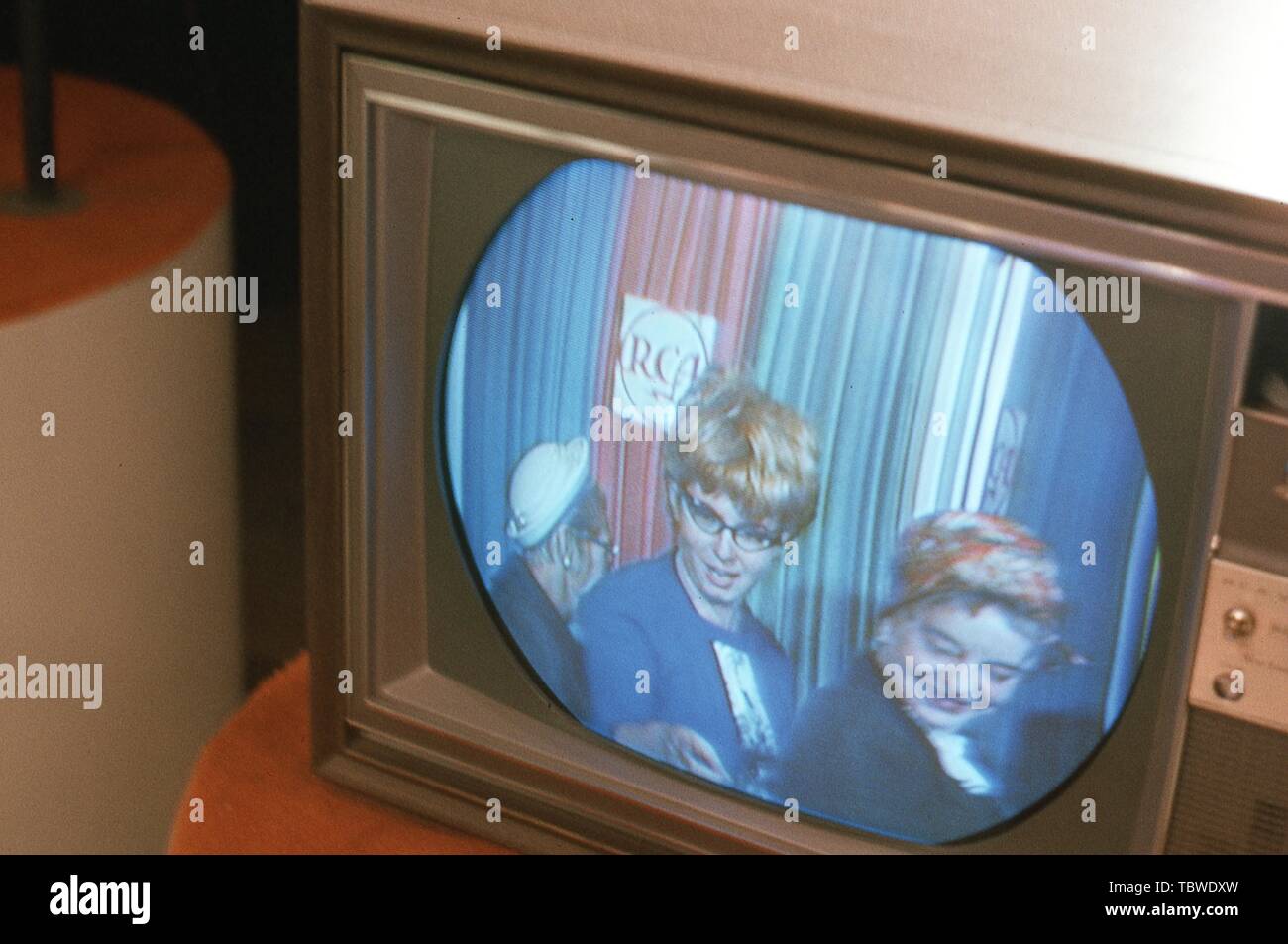 Visitors see themselves broadcast in color for the first time from monitor sets lining the entrance to the Color Television Communications Center exhibit at the RCA Pavilion of the New York World's Fair, Flushing Meadows, Queens, New York, August, 1965. () Stock Photo