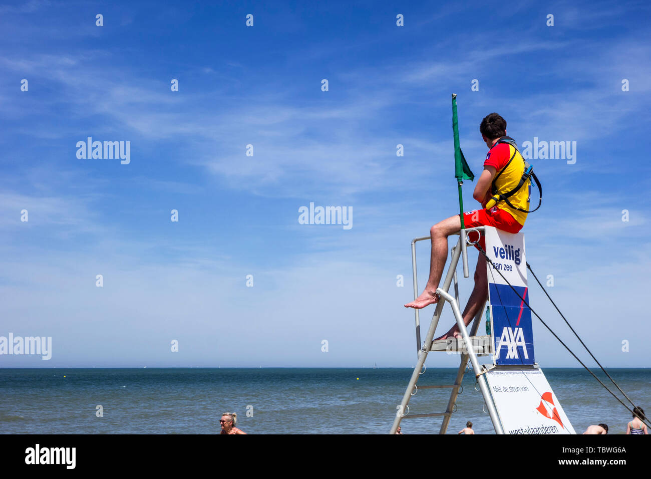 Beach lifeguard supervising bathers and swimmers along the Belgian North Sea coast from portable high chair / tower, Belgium Stock Photo