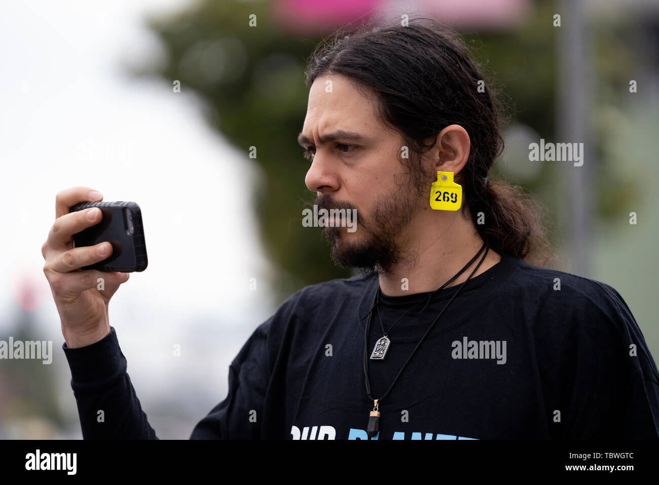 An animal rights activist wears a cattle ID ear tag during the 9th Annual National Animal Rights Day in Los Angeles, California.  The event included a memorial ceremony and a funeral march for animals that are slaughtered for meat consumption, die in research laboratories and the cosmetics industry. Organizers called to end animal cruelty and suffering. Stock Photo