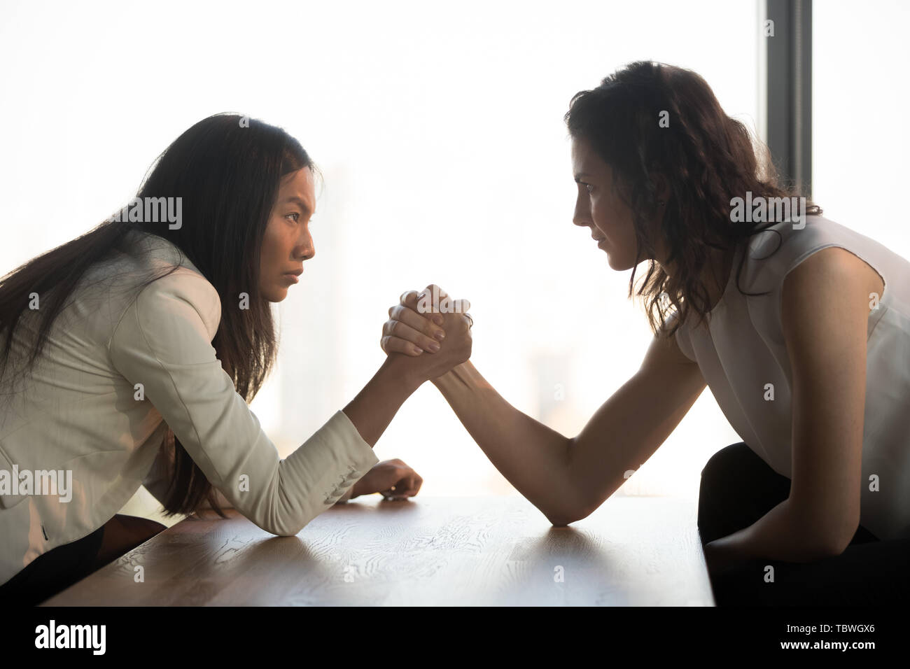 Strong women arm wrestle at work struggle for leadership Stock Photo