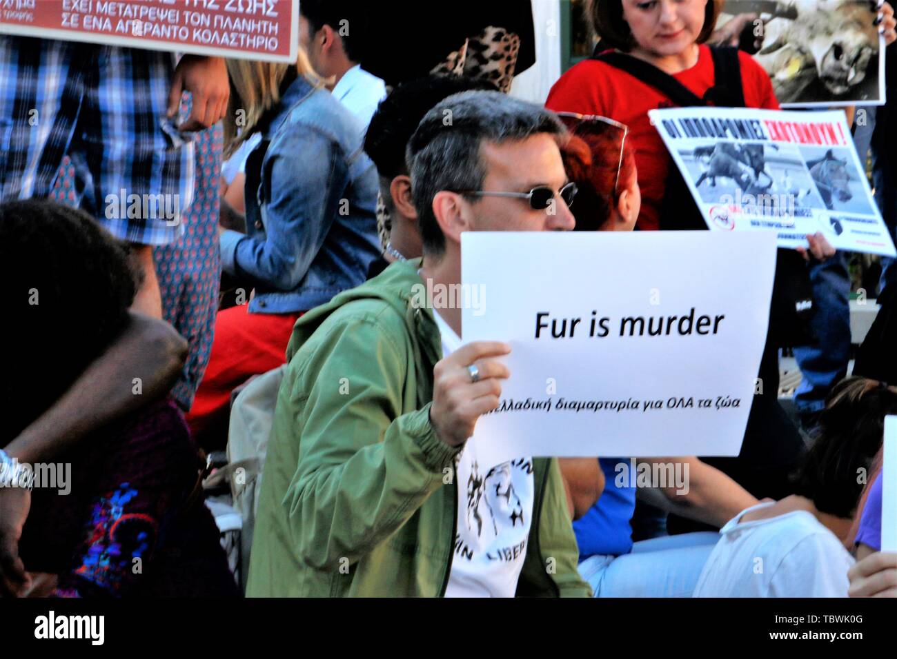 A protester holds a placard that says fur is murder during the demonstration at monastiraki square. Vegan activists demonstrate in front of the Monastiraki square in Athens, promoting the vegan way of life and demonstrating against meat consumption. Stock Photo