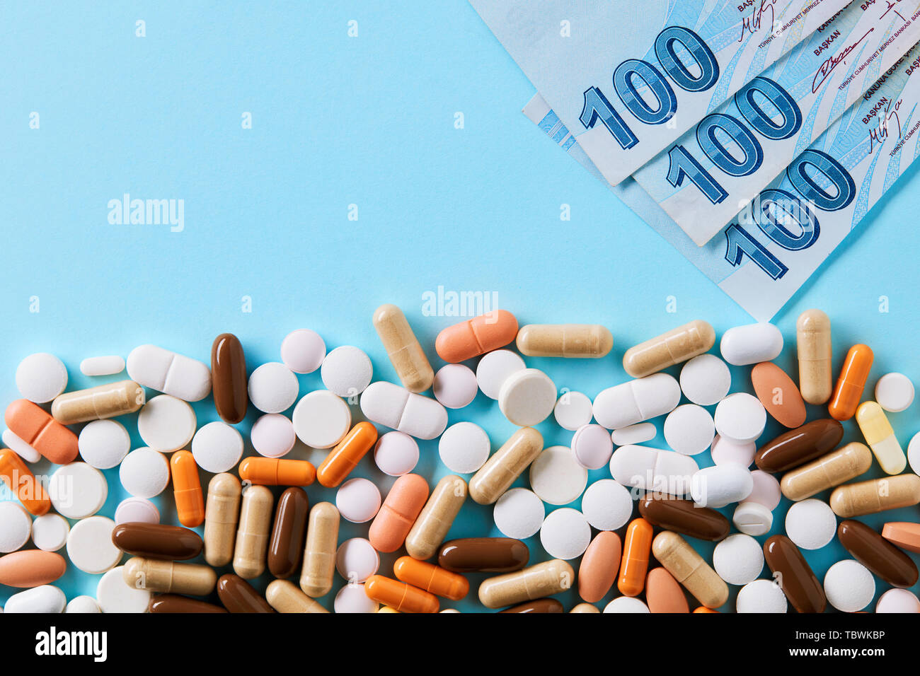 Hundred Turkish Lira bills over the medical pills. Expensive medicine and healthcare industry concept. Overhead macro view with copy space. Stock Photo