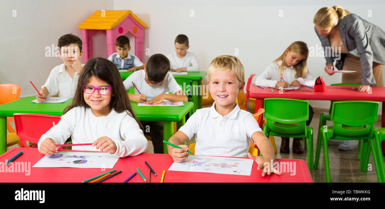 Portrait of happy pupils working in classroom at elementary school ...