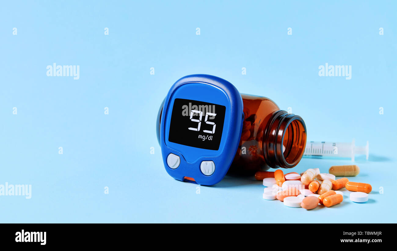 Glucose meter displaying ideal blood sugar range, colorful medical pills  spilling out of drug bottle and a syringe on blue background with copy  space Stock Photo - Alamy