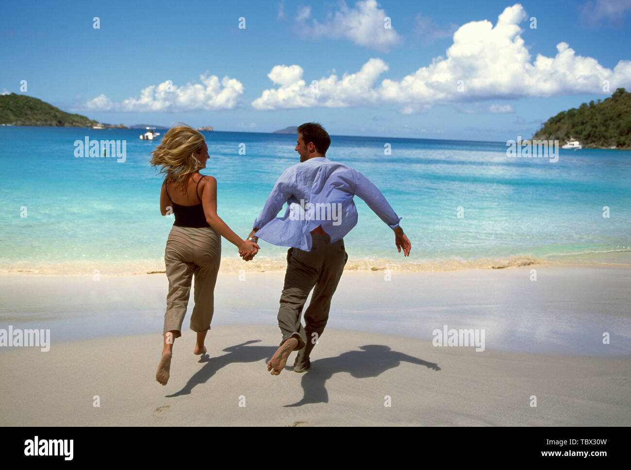 Couple running on beach holding hands Stock Photo - Alamy