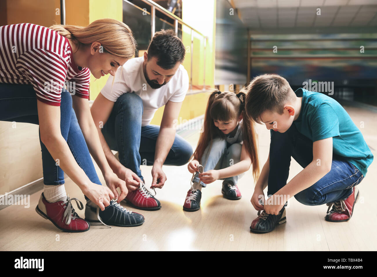 Family changing shoes before playing bowling in club Stock Photo