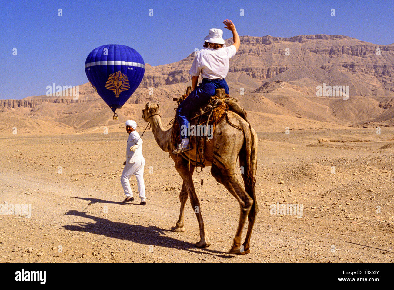 Photo: © Simon Grosset. Hot air ballooning over the Valley of the Kings, Luxor, Egypt. A tourist follows the balloon on camelback. Archive: Image digi Stock Photo