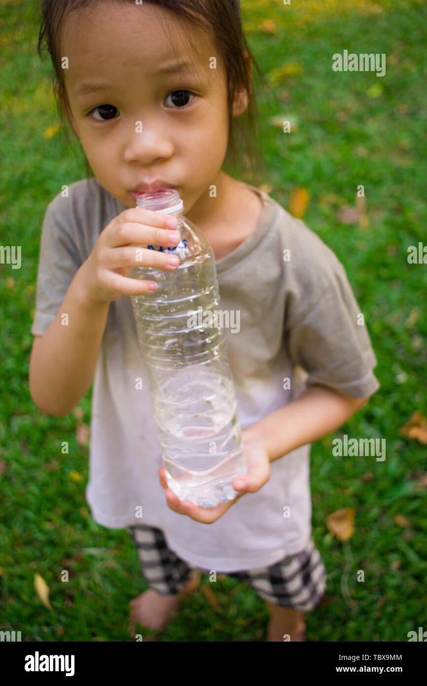 little children drinking water from bottle in green park. High resolution image gallery Stock