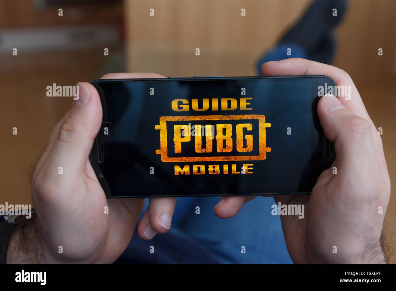 LOS ANGELES, CALIFORNIA - JUNE 3, 2019: Lying Man holding a smartphone and playing the PlayerUnknown's Battlegrounds PUBG game on the smartphone scree Stock Photo