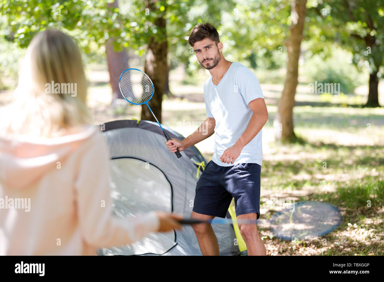 young couple playing badminton by their tent Stock Photo