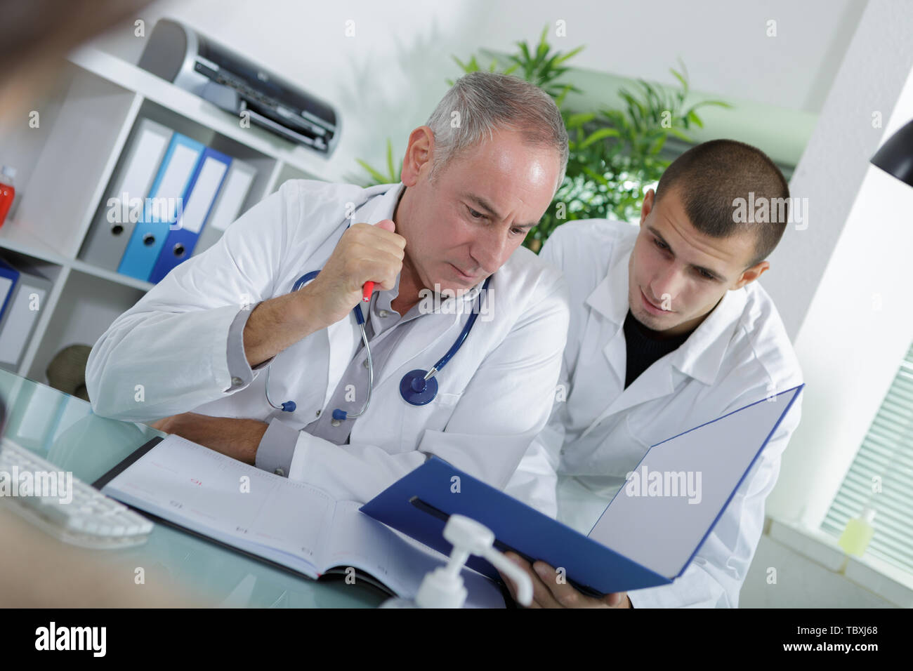 apprentice and doctor checking a patients folder Stock Photo