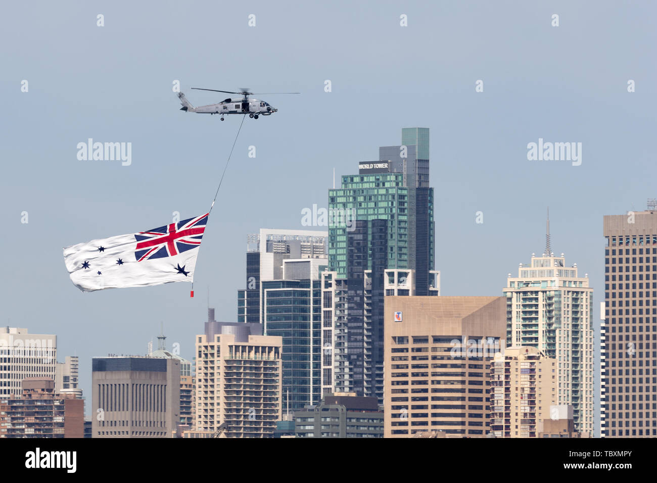 Royal Australian Navy (RAN) Sikorsky S-70B-2 Seahawk Helicopter N24-001 flying the White Ensign of the RAN over Sydney Harbour. Stock Photo