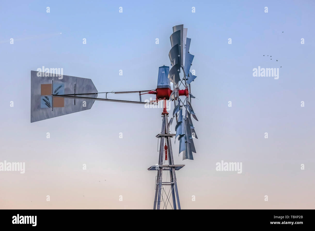 Side view of a windpump with the blades and tail connected to a red rotor hub. Stock Photo