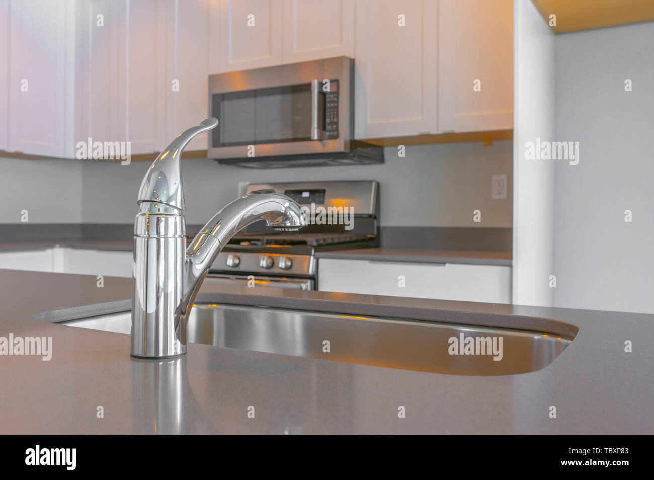 Modern kitchen interior with faucet and sink on the glossy countertop ...