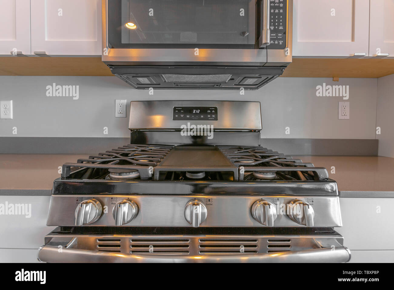 Close up of wall mounted microwave and cooktop of a range inside the