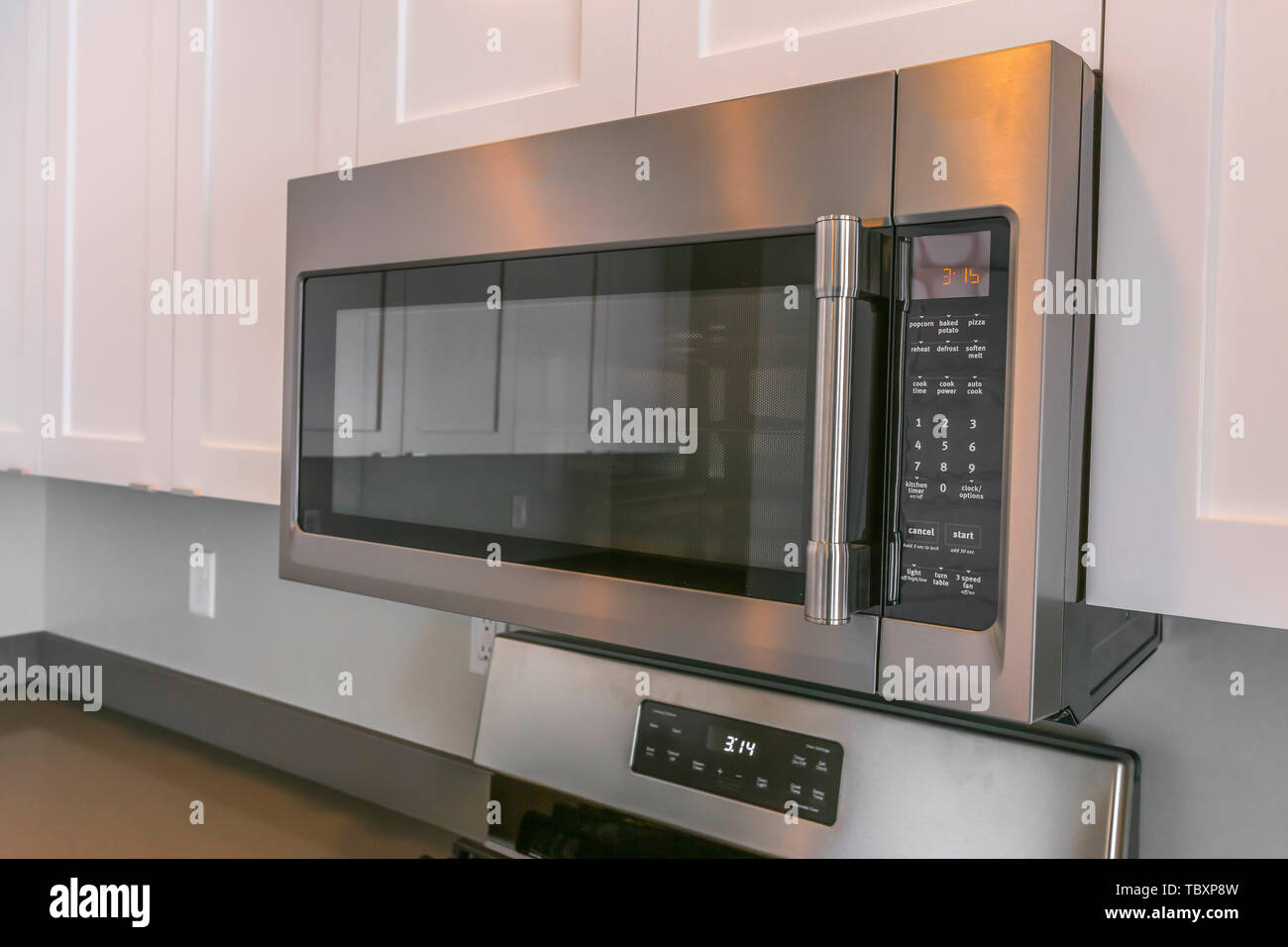 Close Up Of A Microwave And White Cabinets Mounted On The Wall Of